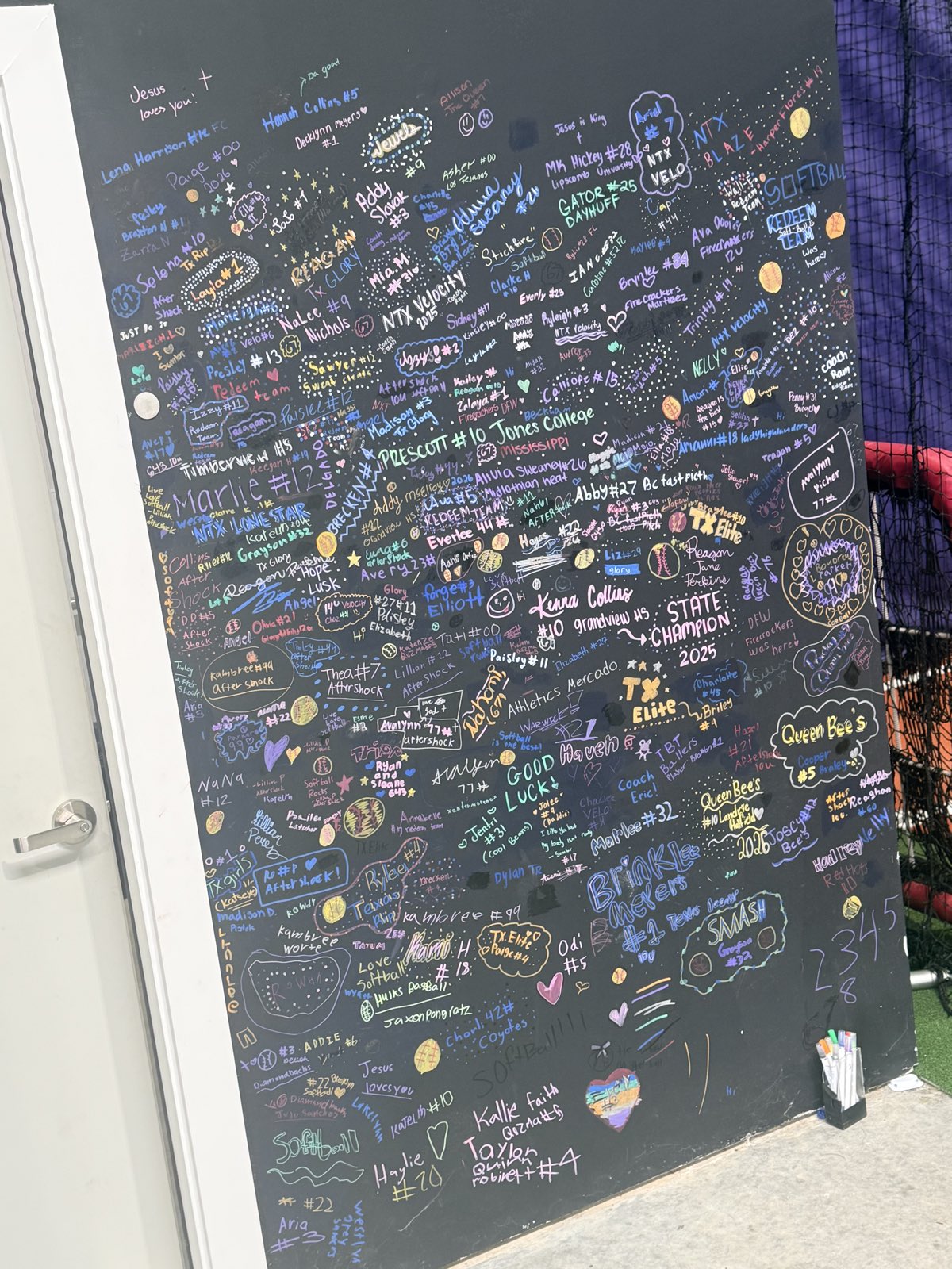 Signature wall at Velocity Fastpitch Academy covered in autographs from travel teams and players who train here